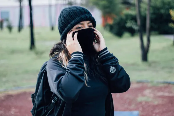 Parktaki Latin üniversiteli kız yüz maskesi takıyor.