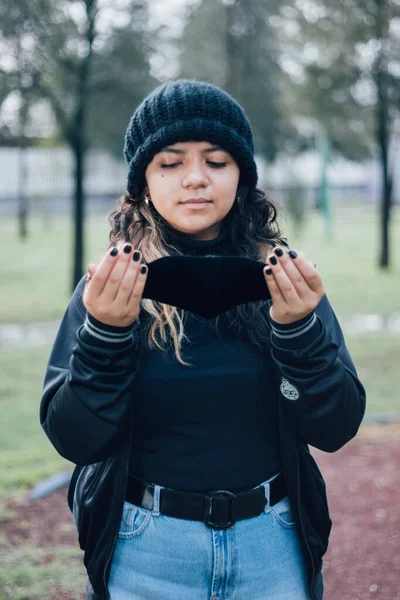 Parktaki Latin üniversiteli kız yüz maskesi takıyor.