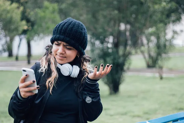 Parktaki Latin üniversiteli kız telefonuyla internette geziniyor.