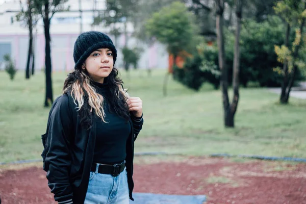 Düşünceli Latin üniversiteli kız parkta yürüyor.