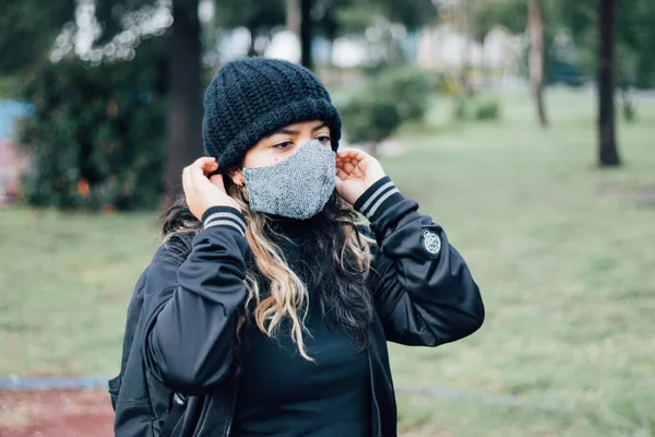 Parktaki Latin üniversiteli kız yüz maskesi takıyor.
