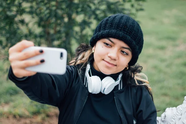 Parktaki Latin üniversiteli kız telefonuyla selfie çekiyor.