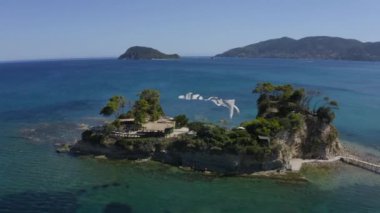 Üzerinde Akdeniz kafesi olan küçük yeşil bir adanın hava görüntüsü. Test uçuşu, uçmak.