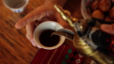 Mans hands pour some tea or coffee from arabic teapot into the cup. High quality FullHD footage