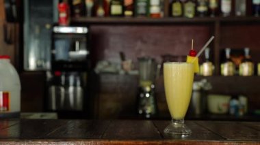 Mans hand puts yellow glass cocktail , pineapple and coconut cocktail on rack. High quality FullHD footage