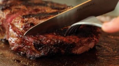 Lezzetli bir et kazığını yakın çekimde bir parça çatal ve bıçakla kesilir. Yüksek kaliteli FullHD görüntüler