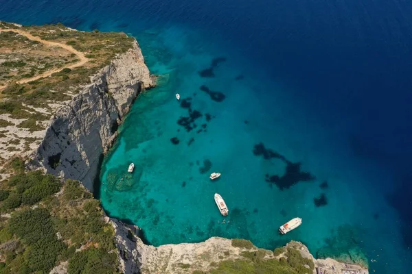 White boats, yachts in blue turquoise ocean lagoon, rocky mountain shore, aerial. High quality image.