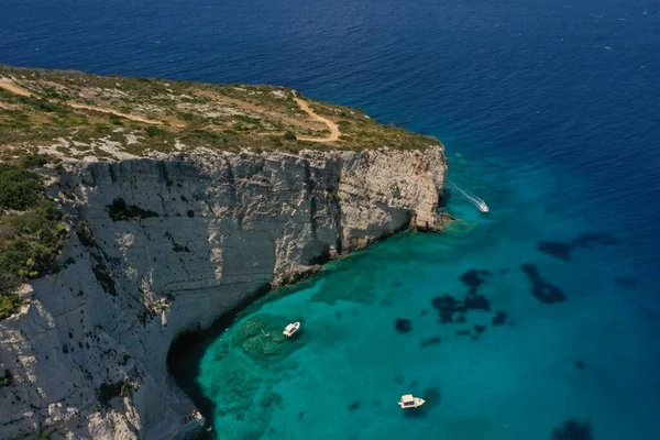 White boats, yachts in blue turquoise ocean lagoon, white rocky mountain shore, aerial. High quality image.