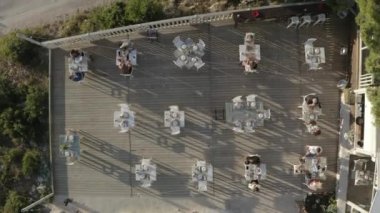 Drone top shot of a cafe with many tables, people having dinner outdoors..