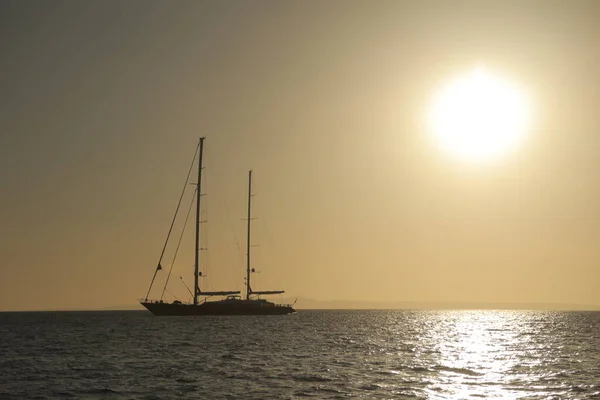 Sailing ship with lowered sails in the sunset with huge sun in the golden hour....