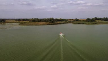 Aerial shot following speed boat in the dark green lake, entering river, Ukraine. High quality FullHD footage