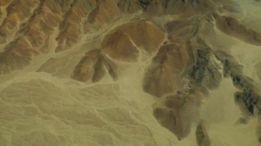 Aerial shot from airplane of mysterious Nazca desert lines, geoglyphs near rocks..