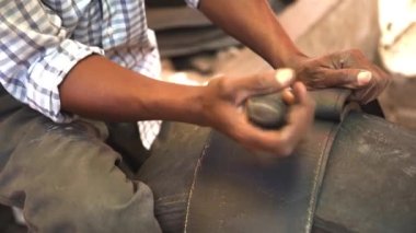 Black mans hands cut black wheel tires in stripes with knife, recycle materials..