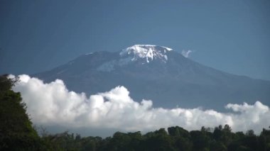Long time lapse of white clouds move below majestic Kilimanjaro snowy mountain...