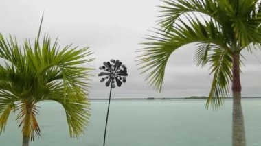 Outdoor wind fan propeller moving in different sides green palms and milky ocean..