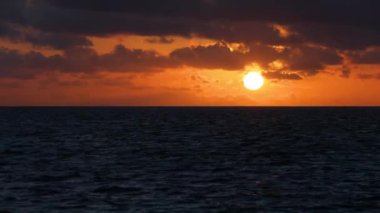 Time lapse of sunset, sun locked in one place, very vivid strong crimson colors..