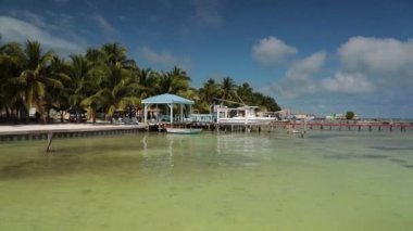 Caribbean embankment with white boat, long wooden pier, view from the water..