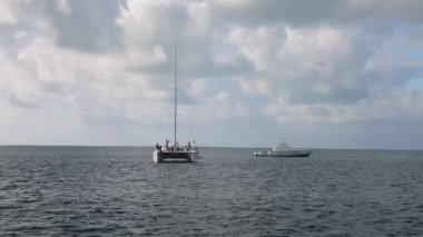 Beautiful white big catamaran with empty mast and small luxury yacht in open sea..