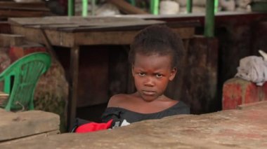 Afrikalı küçük bir kız kenar mahallelerdeki masanın arkasında saklanıyor, Afrikalı fakir bir çocuk...