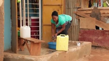 Afrika gecekondu mahallesinde, fakir Uganda Kampala bölgesinde siyah kadın paçavraları sıkıyor...