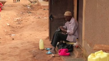 Siyah adam Afrika gecekondu mahallesinde ayakkabı temizliyor, fakir Uganda Kampala hayatı...