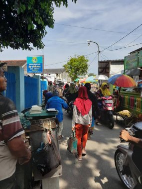 Yoldan geçen araçlarla dolu bir Asya pazarındaki cadde.