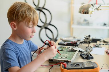 Genç harika çocuk. 5 yaşında. Devre kartını evde çoklu sayaçla onarıyor ve onarıyor.