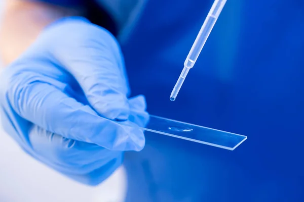 Närbild forskare med hjälp av engångspipett för att ladda biologiska prover på ett glas. DNA-test, familjeband koncept — Stockfoto