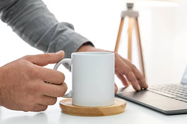 Trabajar en casa y beber café de taza de cerámica blanca de 10 oz. Copia de taza blanca espacio maqueta para su diseño. Concepto de negocio con escritorio de oficina y portátil Imagen de archivo