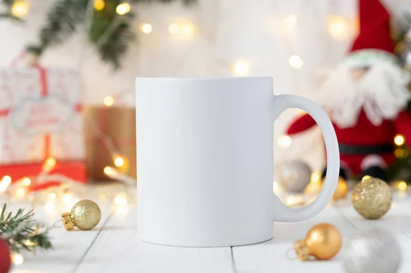 Taza de té de cerámica blanca maqueta con juguete de Santa Claus, decoraciones de Navidad de invierno y espacio de copia para su impresión. Vista frontal 10oz taza de fondo para contenido promocional de Navidad Imágenes de stock libres de derechos