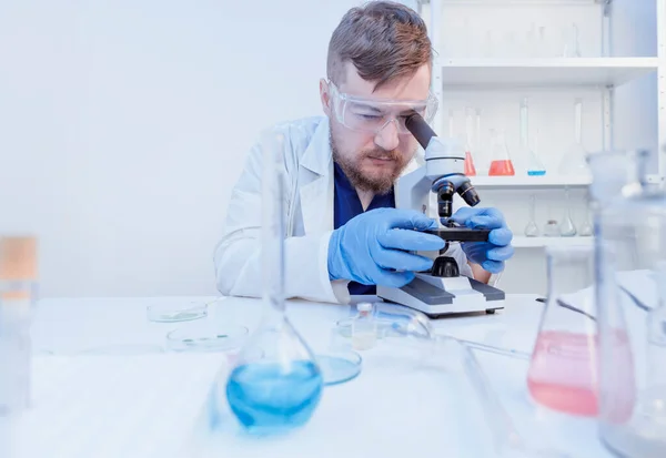 Doktorn gör ett DNA-test med prover i laboratorium, tittar på mikroskop — Stockfoto
