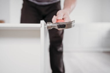 Marangoz hizmetleri konsepti. Mutfak mobilyaları monte ediliyor. Çekiçle çekmeceler