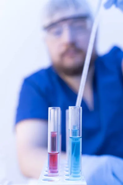 Vaccinkliniska prövningar. Doktor droppande blå vätska i labbet röret och tittar på reaktion, experiment — Stockfoto