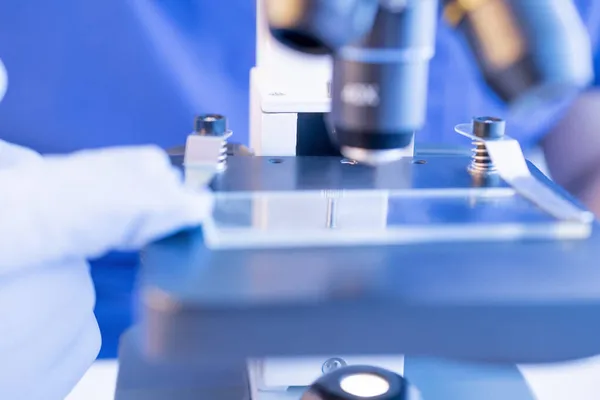 Laboratorietester av blod. Selektiv fokus läkare hand hålla mikroskop glas bild för blodprov — Stockfoto