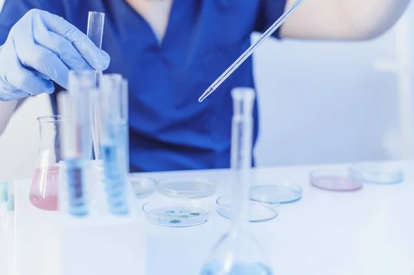 Exames laboratoriais de amostras de sangue. Cientista segurar a pipeta e soltar o líquido químico para pesquisa e análise em um laboratório. — Fotografia de Stock