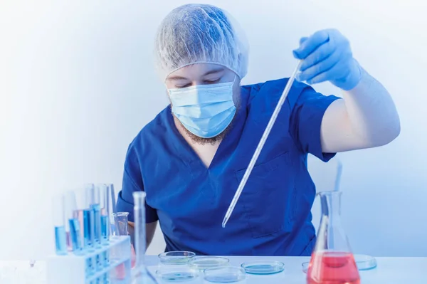 Exames laboratoriais de amostras de sangue. Retrato de Cientista em máscara e luvas segurar a pipeta e soltar o líquido químico para pesquisa e análise em um laboratório. — Fotografia de Stock