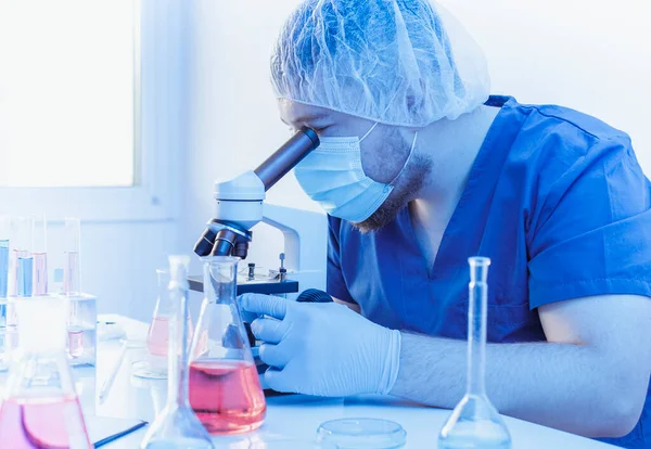 Mikrobiolog forskare bär medicinsk kostym analysera genetik prov med hjälp av mikroskop i mikrobiologi laboratorium. Arbeta med vaccin på labbet. — Stockfoto