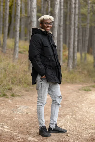 La naturaleza otoñal con la humana. Joven afroamericano caminando en el bosque otoñal — Foto de Stock