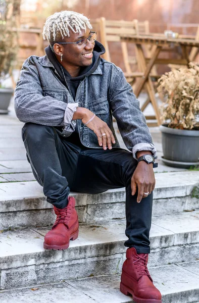 Sonriente hombre afroamericano con rastas se sienta en los escalones de afuera. Melinial de generación joven — Foto de Stock