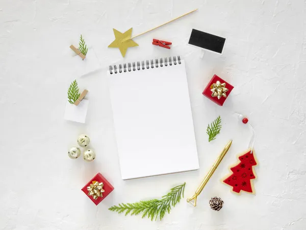 Geöffnetes Spiralattrappen-Notizbuch und Weihnachtsbaumzweige auf weißem Hintergrund, umrahmt von Weihnachtsschmuck. Vorlage für Neujahrsgrußkarte. Frohe Weihnachten und ein gutes neues Jahr — Stockfoto