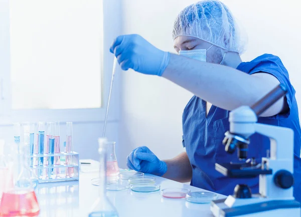 Protrato ainda vivo do pesquisador científico médico de uniforme e luvas trabalhando em laboratório sobre vírus e vacina coronavírus covid 19 com tubo de ensaio frasco. Mistura de amostras com pipeta — Fotografia de Stock