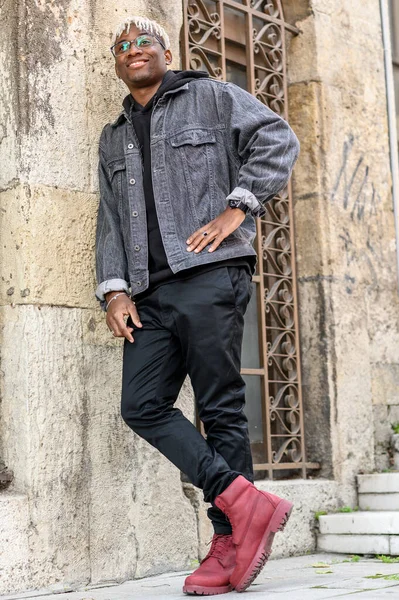 Conceito de juventude do ensino médio. Homem afro-americano sorridente com dreadlocks relaxado contra a parede. Retrato de comprimento total de menino adolescente — Fotografia de Stock