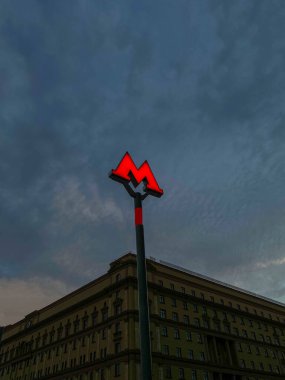 Gece şehrinde, karanlık gökyüzünün arka planında metronun girişinin parlak kırmızı işareti..