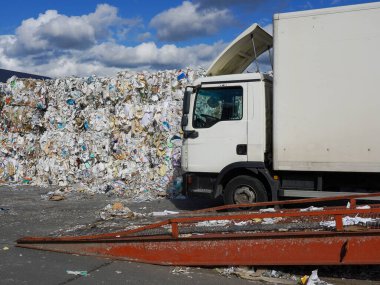 Beyaz kamyonun yanında büyük miktarda atık kağıdın fotoğrafı..