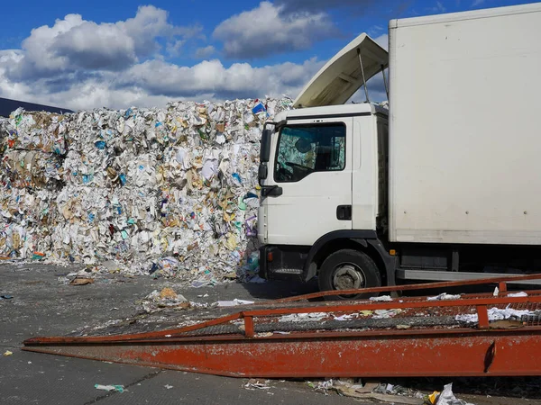 Beyaz kamyonun yanında büyük miktarda atık kağıdın fotoğrafı..