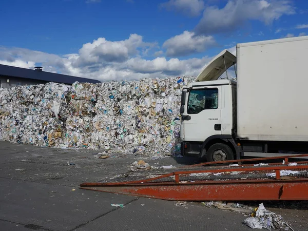 Beyaz kamyonun yanında büyük miktarda atık kağıdın fotoğrafı..