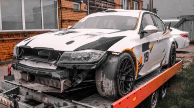 Sokakta bir karavanda kaza yapmış beyaz bir spor arabanın fotoğrafı..