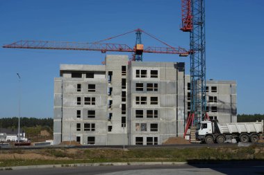 Turnaların ve inşaat makinelerinin yanına gri bir ev inşa etme süreci.