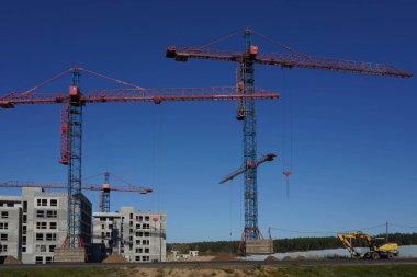 Turnaların ve inşaat malzemelerinin yanına gri bir ev inşa etme süreci.