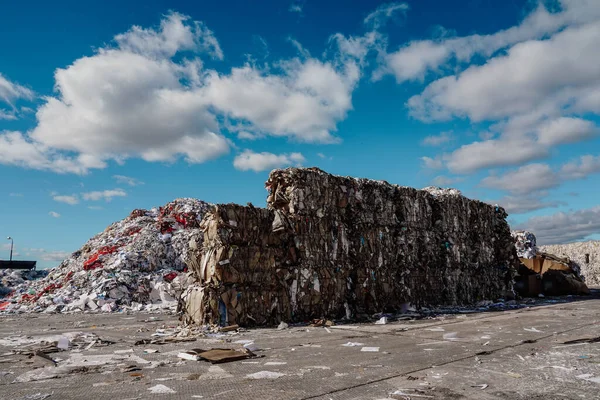 Photo of a large amount of garbage and rubbish at the dump in the street under the blue sky with white clouds.